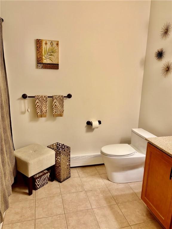 bathroom featuring a baseboard radiator, tile patterned flooring, toilet, and vanity