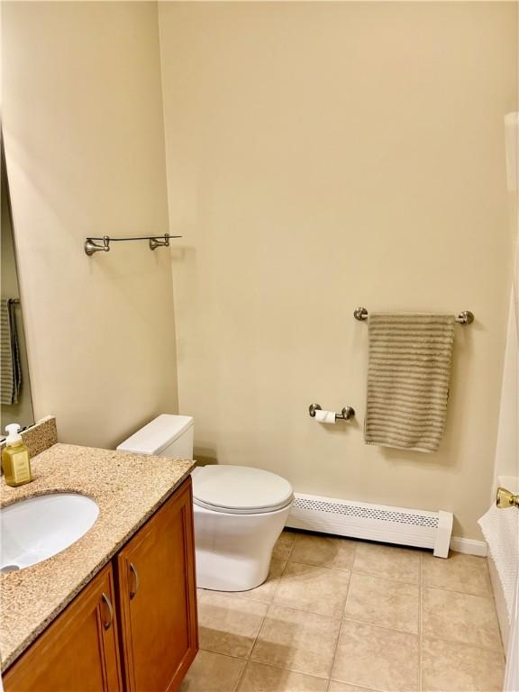 bathroom with baseboard heating, toilet, vanity, and tile patterned flooring