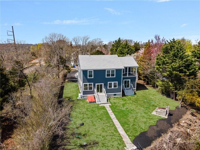 view of front of house with a shingled roof, a balcony, and a front yard