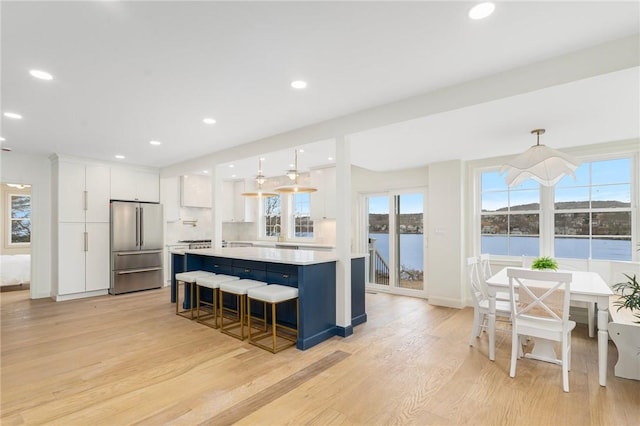 kitchen featuring high end refrigerator, a wealth of natural light, white cabinets, and light countertops