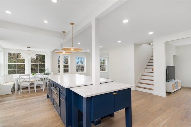 kitchen with hanging light fixtures, light wood-style floors, light countertops, blue cabinetry, and recessed lighting