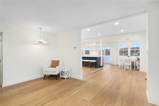 living area with baseboards, light wood finished floors, and recessed lighting