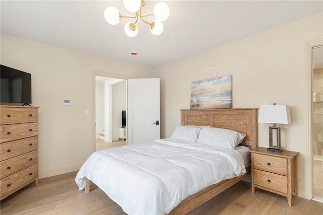 bedroom featuring ensuite bath, baseboards, a chandelier, and light wood-style floors