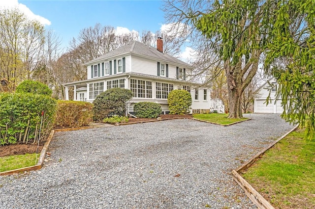 view of front of property featuring a chimney, an outdoor structure, and gravel driveway