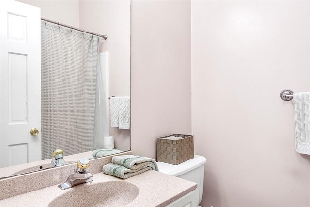 bathroom featuring toilet, curtained shower, and vanity