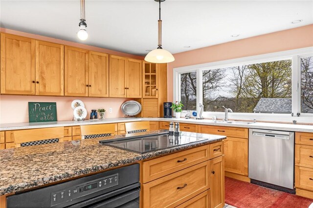 kitchen with a wealth of natural light, light stone countertops, black electric stovetop, and dishwasher