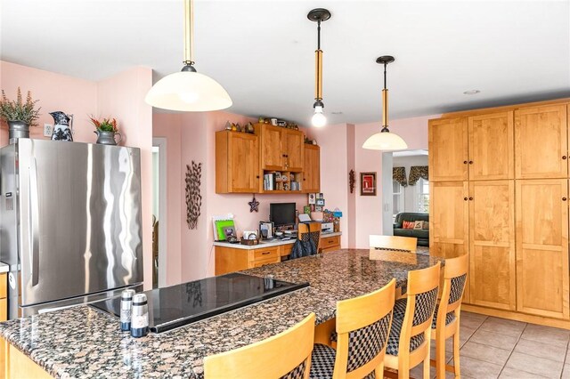 kitchen featuring freestanding refrigerator, pendant lighting, light tile patterned floors, and a kitchen bar