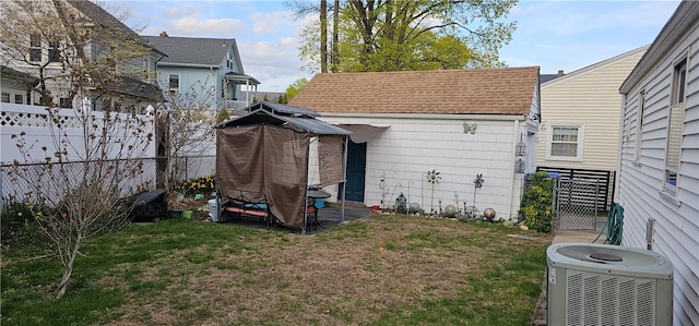 back of house featuring a lawn, central AC, a fenced backyard, and roof with shingles