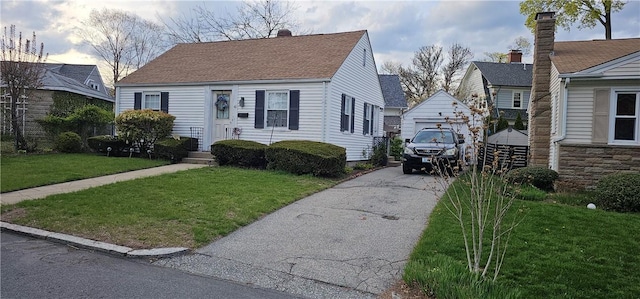 view of front of property featuring a garage, roof with shingles, an outbuilding, and a front lawn