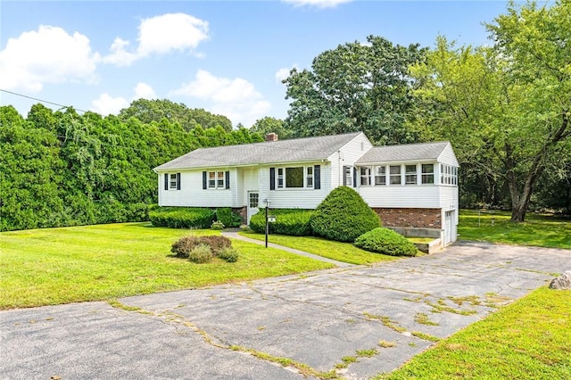 bi-level home with a front lawn, driveway, a chimney, brick siding, and a sunroom