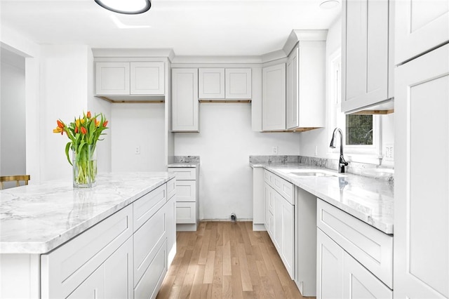 kitchen with light stone countertops, a center island, a sink, and light wood-style floors