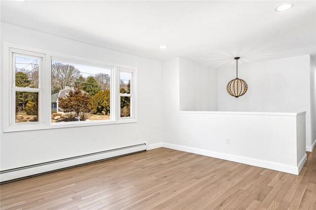unfurnished room with a baseboard heating unit, wood finished floors, baseboards, and recessed lighting