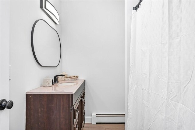 full bath featuring a baseboard heating unit, wood finished floors, and vanity