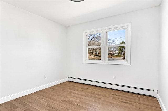 empty room with baseboard heating, baseboards, and light wood-style flooring