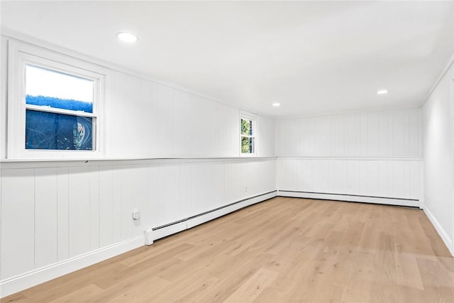 unfurnished room featuring baseboard heating, a decorative wall, and wood finished floors