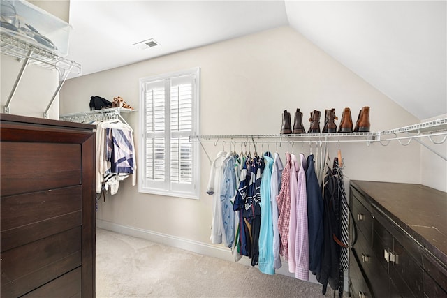 walk in closet with carpet flooring, visible vents, and lofted ceiling