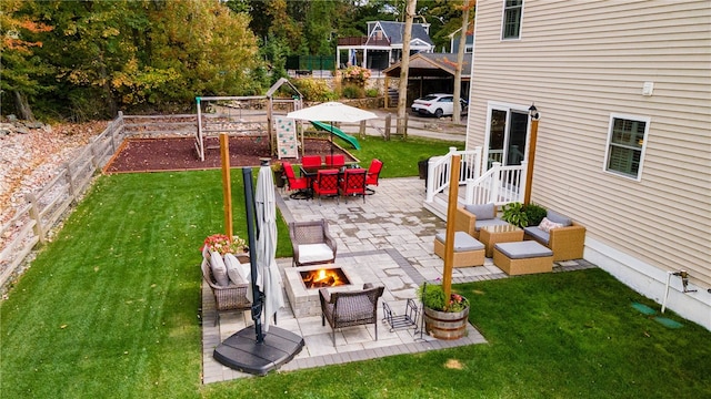 view of yard with a patio, fence, a playground, and an outdoor living space with a fire pit