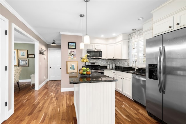 kitchen with backsplash, crown molding, a sink, stainless steel appliances, and white cabinetry