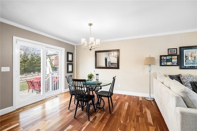 dining area with baseboards, ornamental molding, wood finished floors, and a notable chandelier
