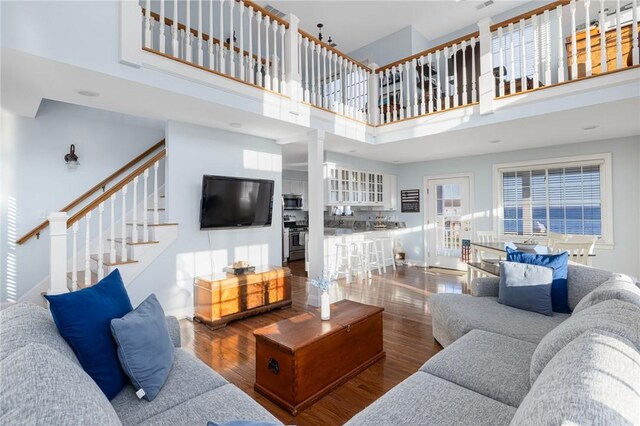 57 Foster St, Warwick, RI 02889 - living room featuring stairway, a towering ceiling, ornate columns, and wood finished floors