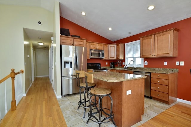 1 Augusta St, Providence, RI 02908 - kitchen featuring appliances with stainless steel finishes, a center island, vaulted ceiling, light stone counters, and light wood-style flooring