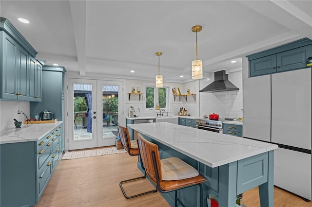 kitchen featuring white fridge, open shelves, wall chimney range hood, and recessed lighting