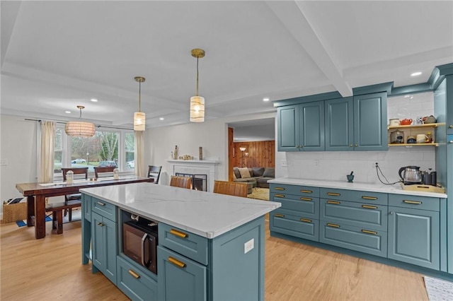 kitchen featuring black microwave, pendant lighting, light wood-type flooring, and backsplash