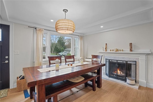 dining space featuring recessed lighting, a tiled fireplace, and light wood-style floors