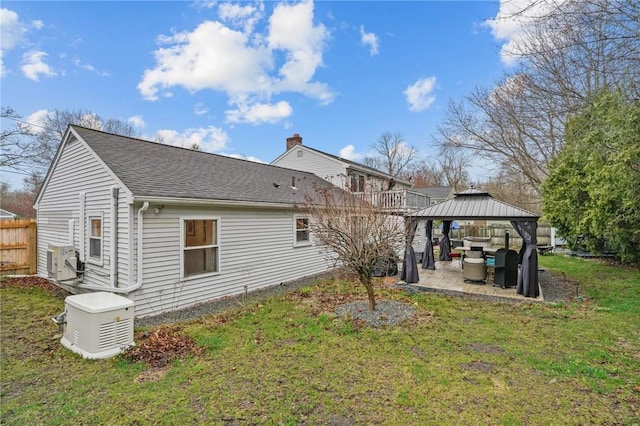 rear view of house featuring roof with shingles, a gazebo, a patio area, and a yard