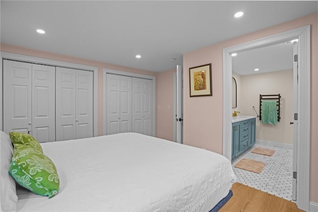 bedroom featuring light wood-type flooring, multiple closets, recessed lighting, and baseboards