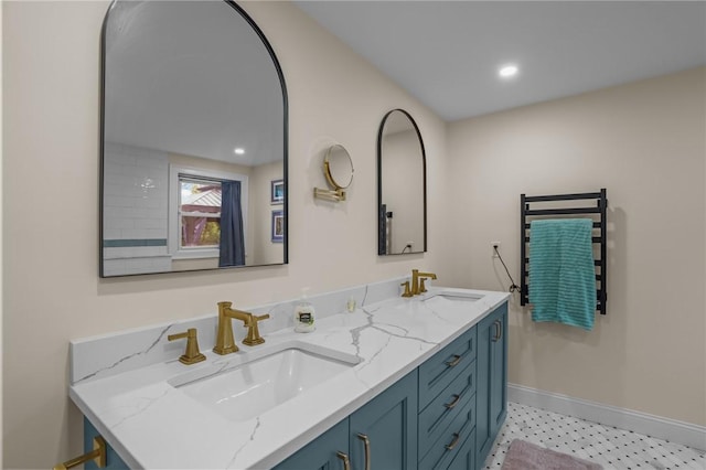 bathroom with baseboards, recessed lighting, double vanity, and a sink