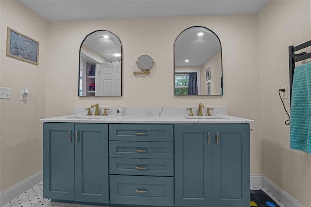bathroom featuring baseboards, double vanity, and a sink