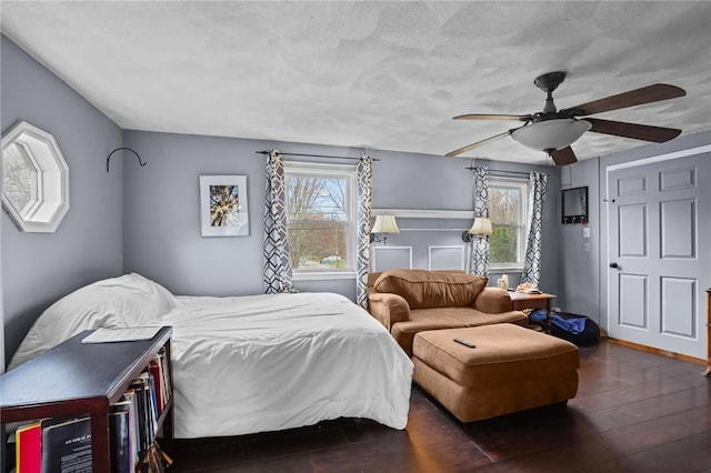 bedroom with ceiling fan, multiple windows, and dark wood-type flooring