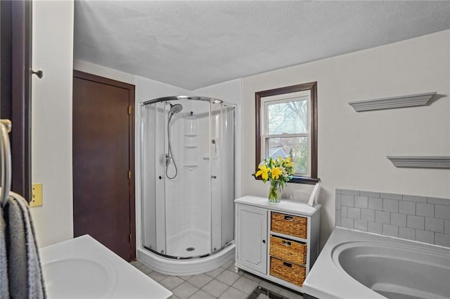 bathroom featuring a sink, a shower stall, a bath, tile patterned floors, and a textured ceiling