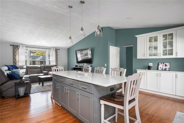 136 Wilde Field Dr, Warwick, RI 02889 - kitchen featuring lofted ceiling, open floor plan, a breakfast bar area, white cabinets, and light wood-style flooring