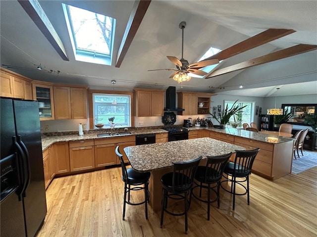 63 Duck Cove Rd, North Kingstown, RI 02852 - kitchen with a peninsula, wall chimney range hood, a sink, black appliances, and a skylight