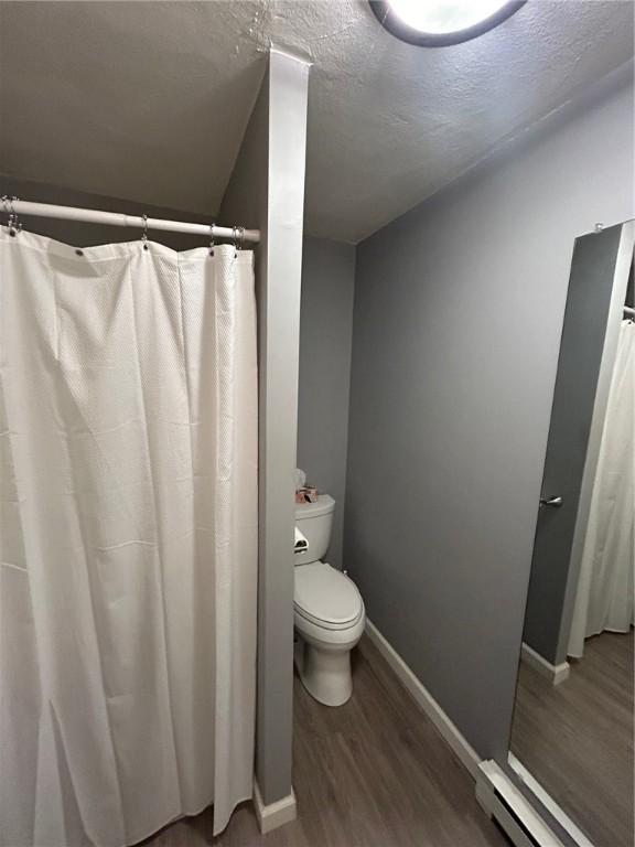 63 Duck Cove Rd, North Kingstown, RI 02852 - full bathroom featuring baseboards, a baseboard heating unit, wood finished floors, and toilet