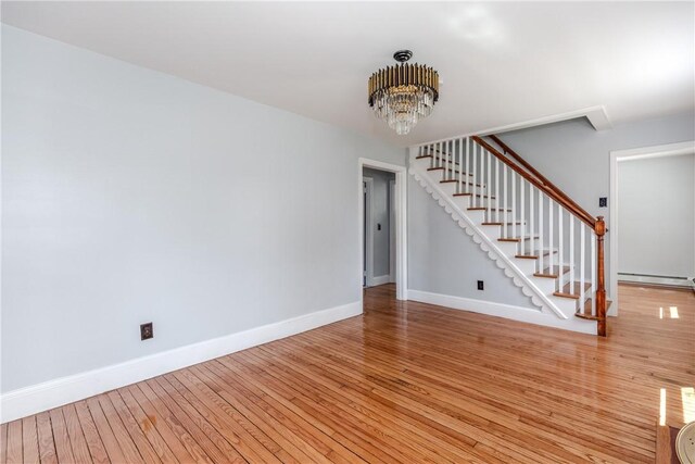 46 Freeman St, Warwick, RI 02886 - unfurnished living room featuring an inviting chandelier, light wood-style flooring, baseboards, and stairway