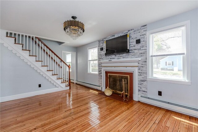 46 Freeman St, Warwick, RI 02886 - unfurnished living room with an inviting chandelier, baseboard heating, stairs, and light wood-style flooring