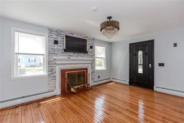 46 Freeman St, Warwick, RI 02886 - unfurnished living room featuring a notable chandelier, a large fireplace, baseboard heating, and light wood-type flooring