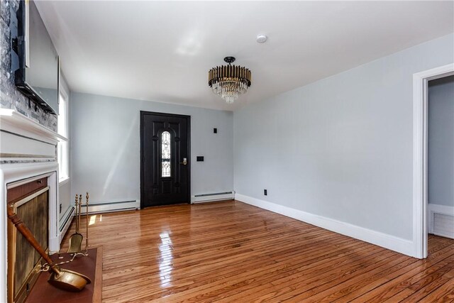 46 Freeman St, Warwick, RI 02886 - entrance foyer with light wood-style floors, a baseboard heating unit, an inviting chandelier, and a fireplace