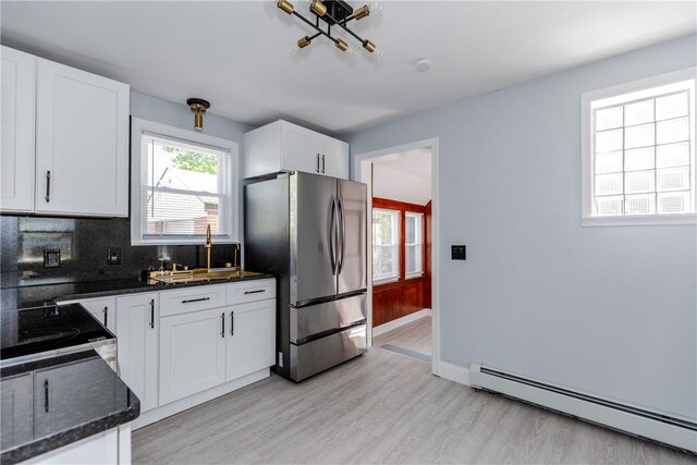 46 Freeman St, Warwick, RI 02886 - kitchen featuring decorative backsplash, baseboard heating, freestanding refrigerator, light wood-style floors, and white cabinetry