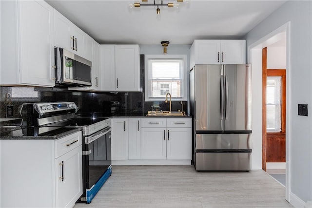 46 Freeman St, Warwick, RI 02886 - kitchen with white cabinets, appliances with stainless steel finishes, a sink, light wood finished floors, and backsplash