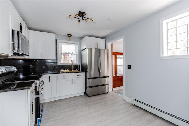 46 Freeman St, Warwick, RI 02886 - kitchen featuring dark countertops, baseboard heating, stainless steel appliances, light wood-type flooring, and backsplash