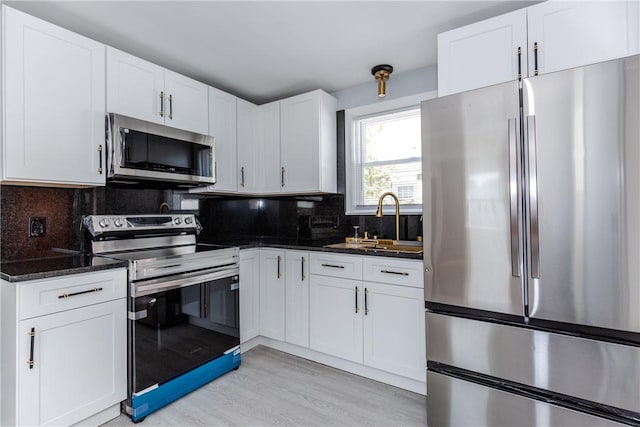 46 Freeman St, Warwick, RI 02886 - kitchen featuring tasteful backsplash, a sink, white cabinets, light wood-style floors, and stainless steel appliances