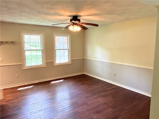 unfurnished room featuring dark wood-style floors, ceiling fan, and baseboards