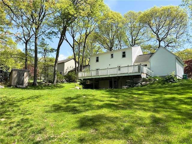 back of house with a wooden deck, a lawn, a storage shed, and an outbuilding