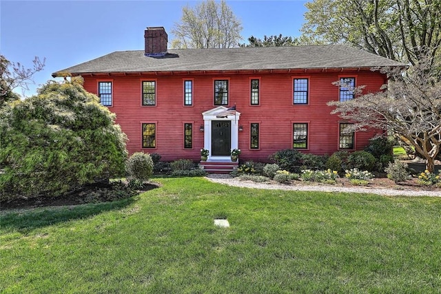 colonial house featuring a front yard and a chimney