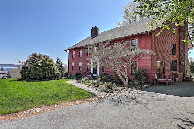 view of front facade featuring a chimney and a front lawn