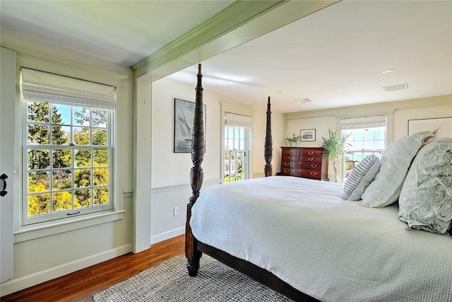 bedroom with baseboards, multiple windows, and wood finished floors